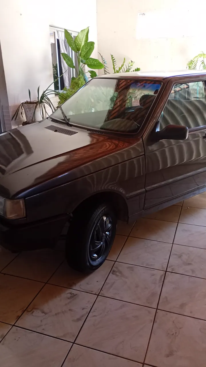 Capô de um carro cinza escuro refletindo o teto da garagem
