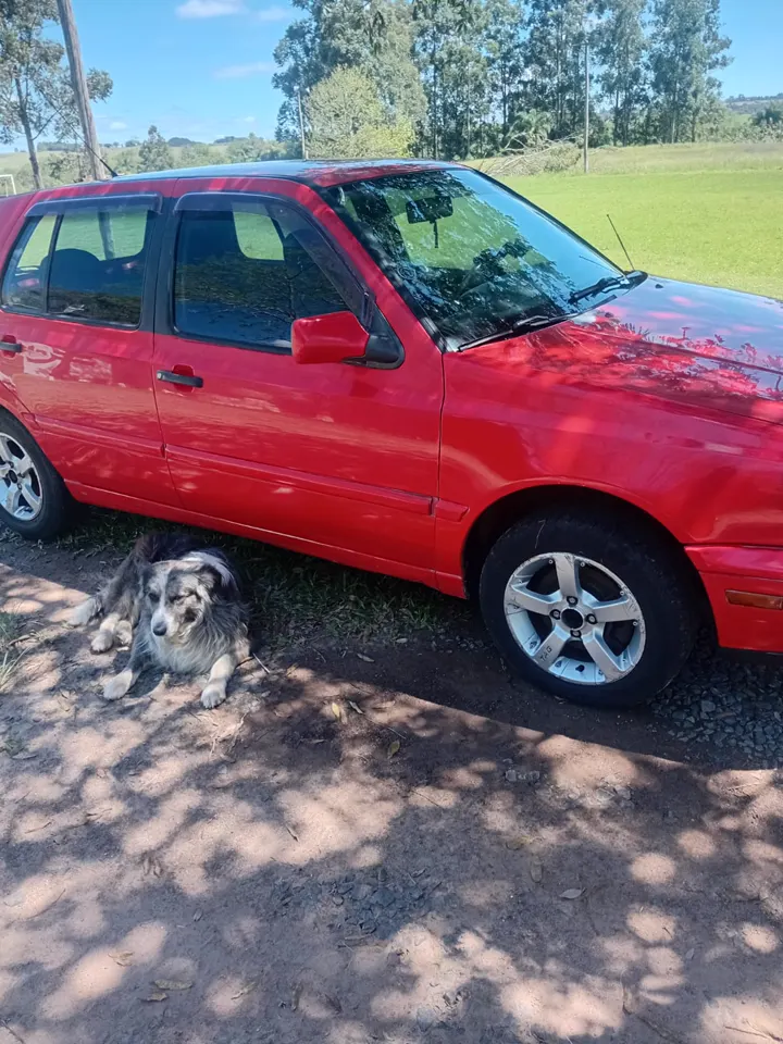 Lateral de um carro vermelho com a pintura brilhando ao ar livre